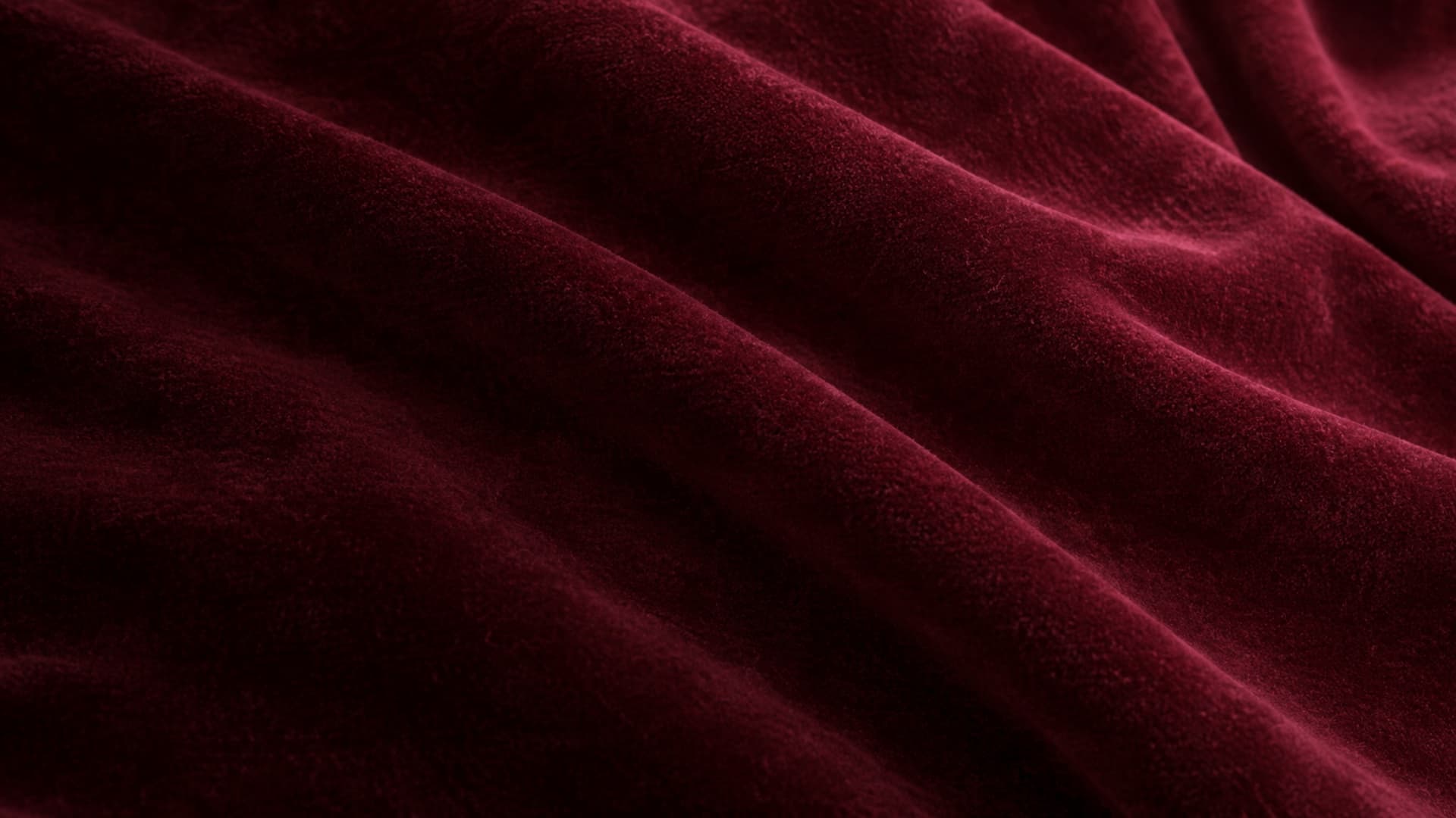 Close-up of burgundy cotton velvet in soft waves under grazing light